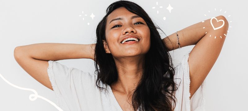 Happy woman with long black hair and a white t-shirt with hands behind her head